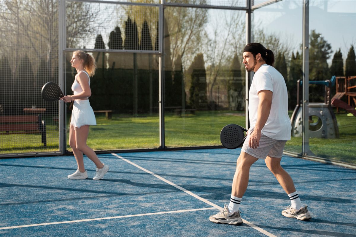 Two people playing doubles pickleball on an outdoor court