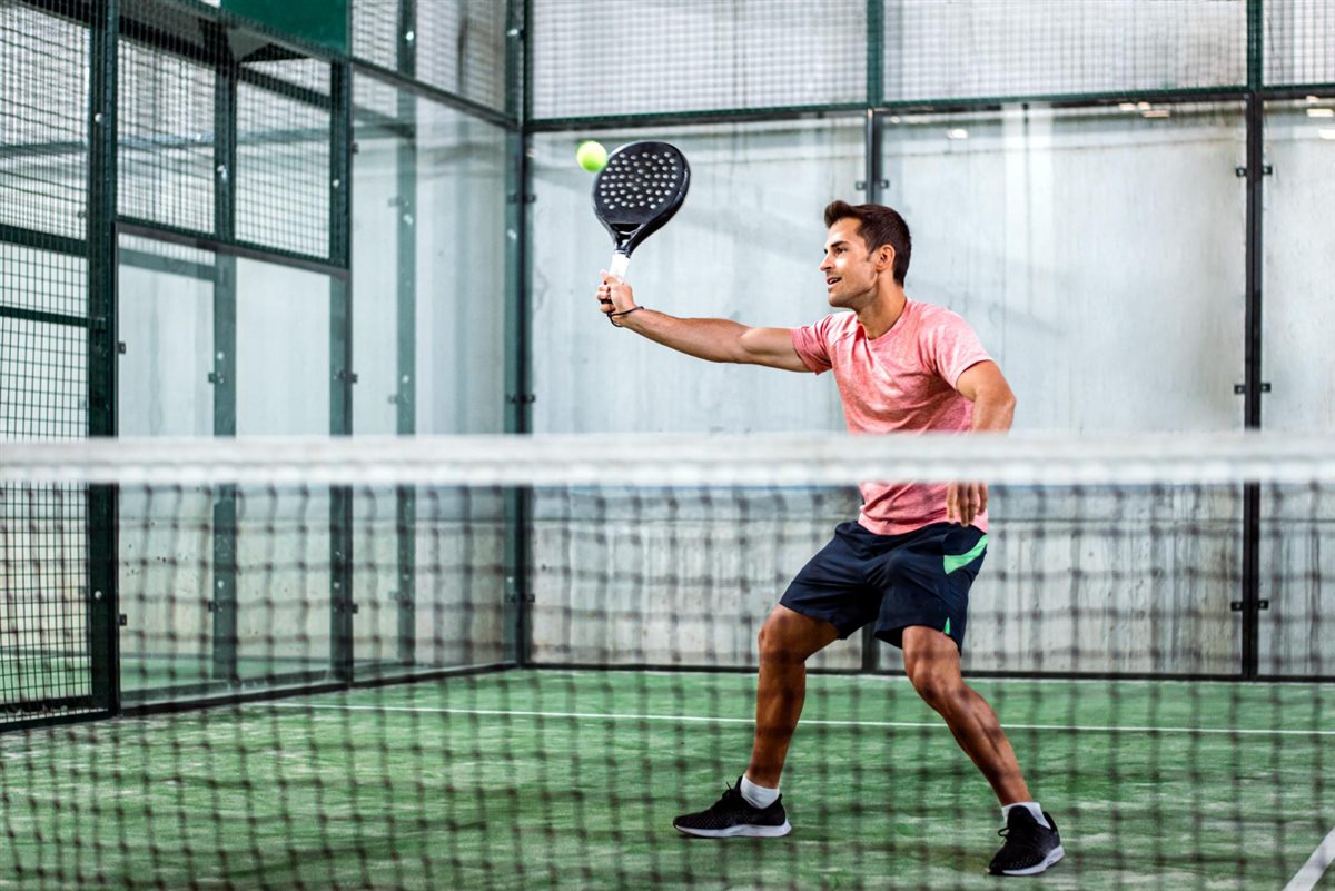 Player holding a pickleball paddle on an indoor court