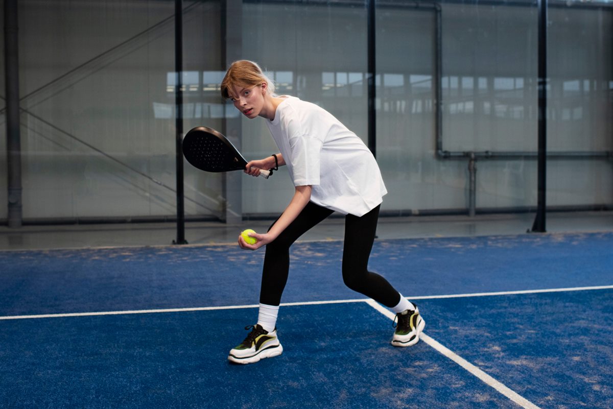 Player serving a pickleball on an outdoor court